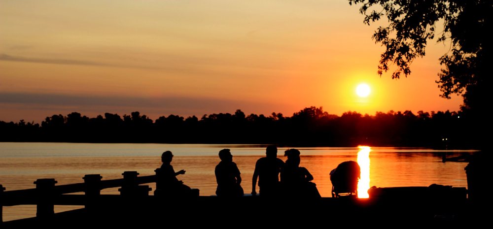 Amigos reunidos frente a la laguna al caer el sol